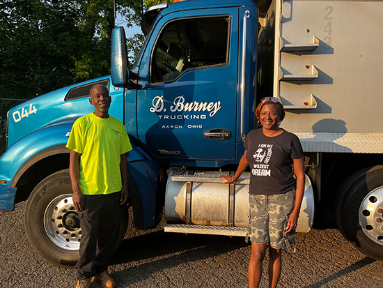 Man and woman standing in front of a semi truck with D. Burney Trucking written on the side
